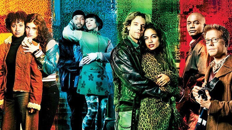 Still from "RENT" - The cast of RENT paired up as the respective couples, colour coordinating with the colour striped colour background