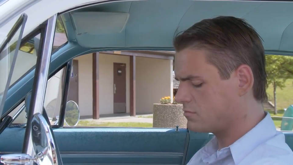 Still from "Caught" - Leading man sitting dejected in car waiting utside restroom