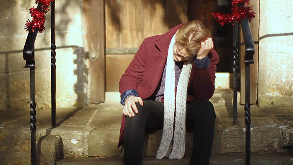 Still from "Goodwill" - Daniel sits on the church steps, frustrated after having walked out of mass