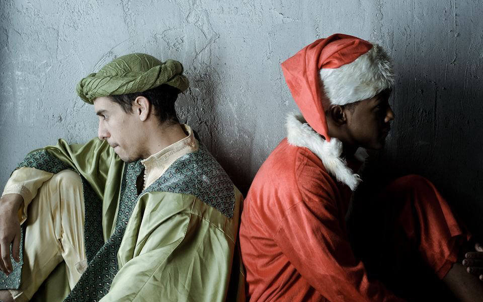 Still from "Lucky Fares" - Balthazar and Santa sit back to back in the jail cell