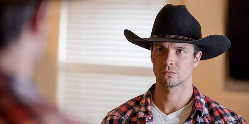 Still from "Dominant Chord" - Adam dons his black cowboy hat while looking in the mirror
